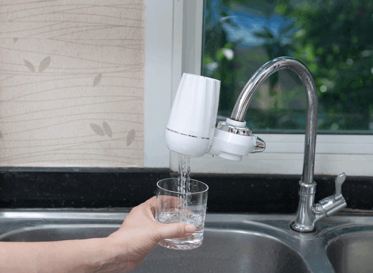 Hand filling glass with tap water.