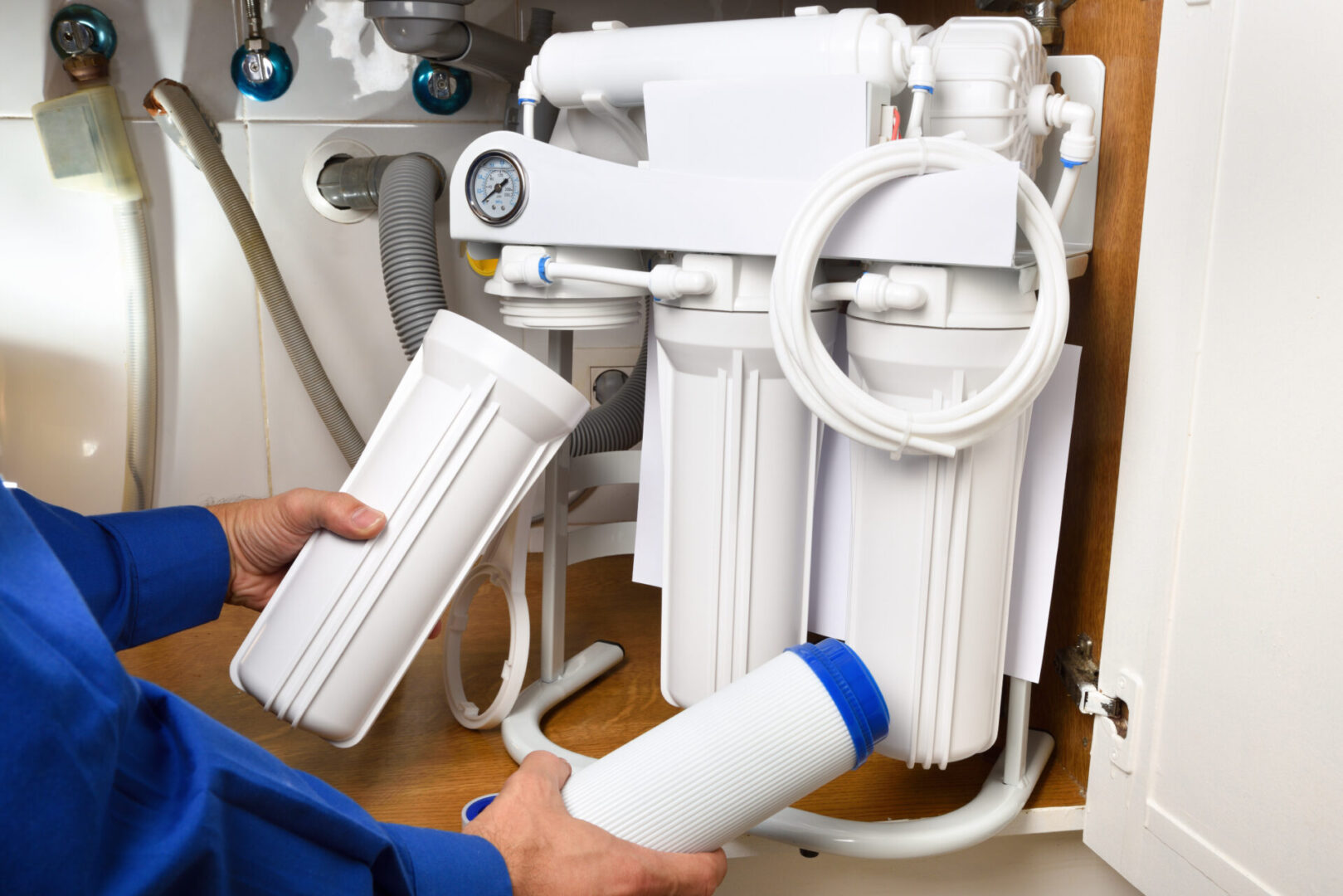 Person replacing under-sink water filter cartridges.