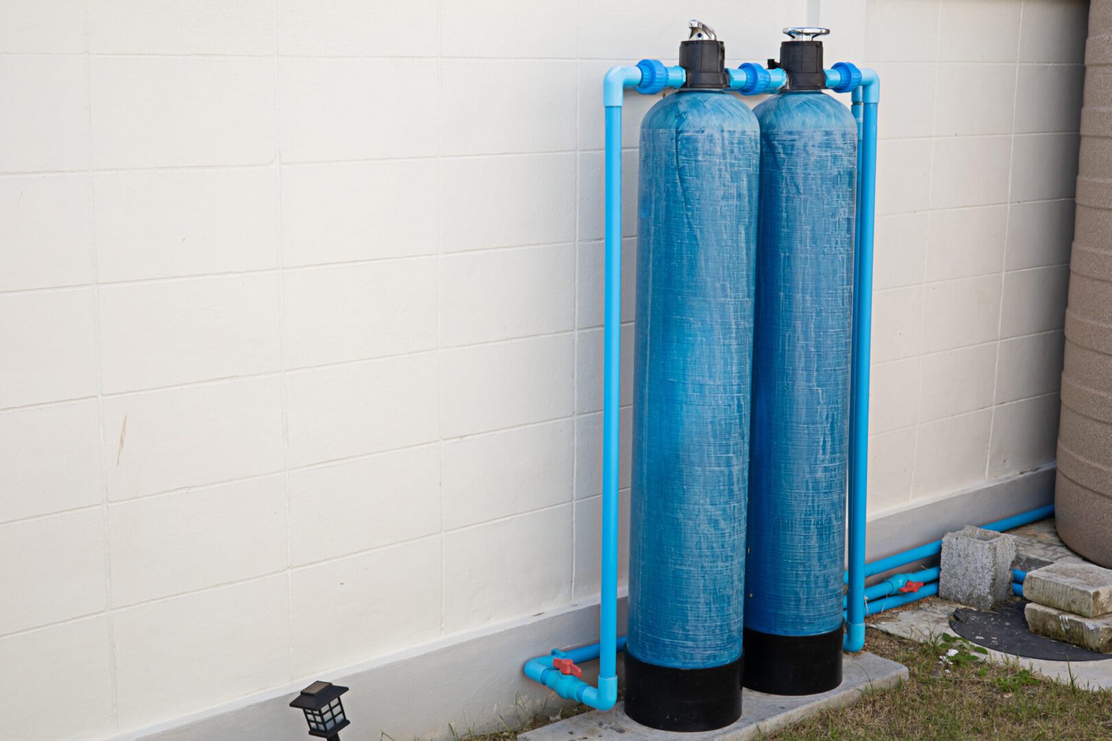 Two blue water filtration tanks outdoors.
