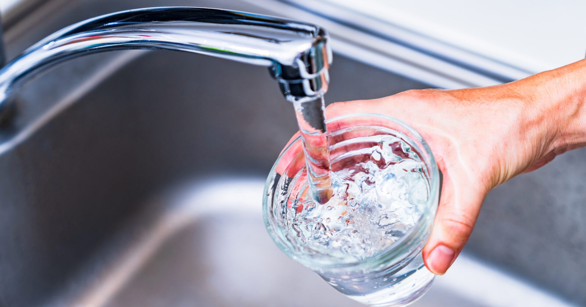 Hand filling glass with tap water.